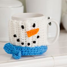 a crocheted coffee mug with a snowman face on it