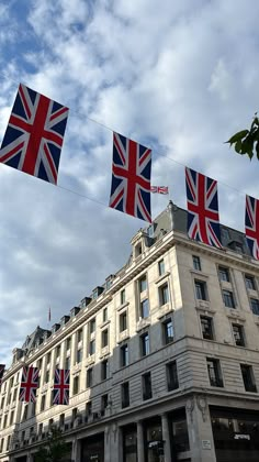 union jack and british flags are flying in the air above a building on a cloudy day