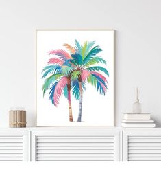 a palm tree with pink, blue and green leaves on it in front of a white wall