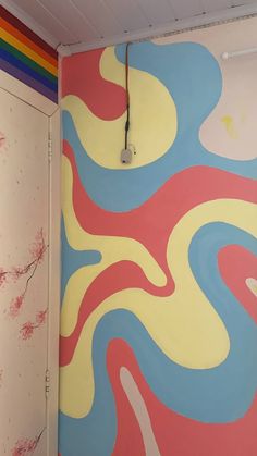 a bathroom with colorful wallpaper and a white toilet next to a rainbow colored door