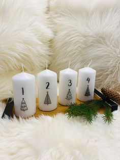 five white candles with numbers on them sitting next to a pine branch and christmas decorations