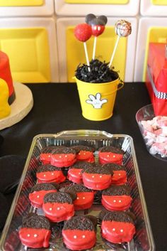 there are many cupcakes in the tray on the table with candy and candies