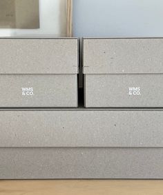 three gray boxes sitting on top of a wooden table