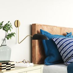 a bed with blue and white pillows on top of it next to a wooden headboard