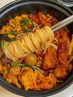 a bowl filled with noodles, meat and vegetables