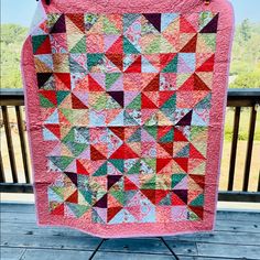 a pink quilt hanging on the side of a wooden deck