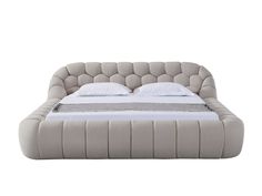 an upholstered bed with white sheets and pillows