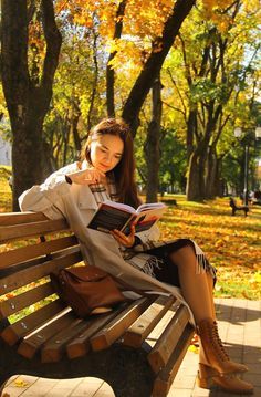 a woman sitting on a bench reading a book