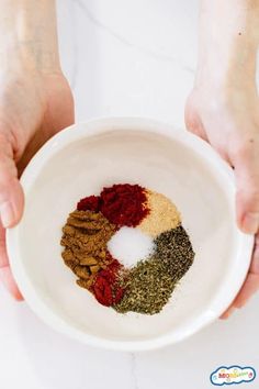 two hands holding a bowl filled with spices