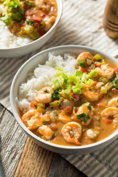 two bowls filled with shrimp and rice on top of a wooden table