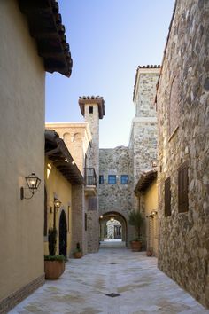 an alley way with stone buildings and potted plants