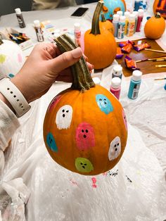 a person holding up a pumpkin decorated with buttons