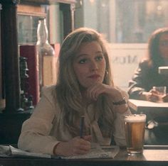 a woman sitting at a bar with a glass of beer