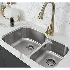 a kitchen sink with two faucets on the side and marble counter top in front