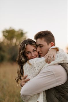 a man and woman hugging each other in a field