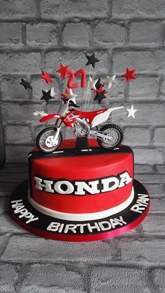 a red motorcycle birthday cake with stars on top and the words honda written on it