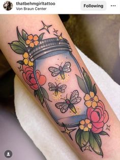 a jar filled with butterflies and flowers on the arm