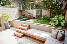 an outdoor living area with stairs, plants and a pool in the middle of it