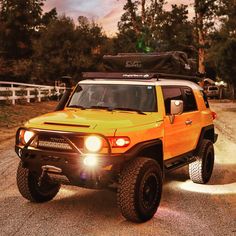 an orange and black four door suv driving down a dirt road