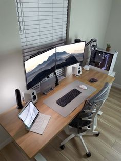 two computer monitors sitting on top of a wooden desk next to a keyboard and mouse