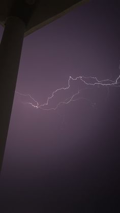 lightning strikes in the night sky over a building and street light on an overcast day