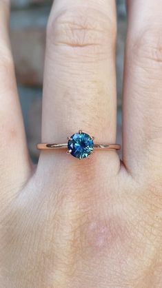 a woman's hand with a ring on it and a blue stone in the middle