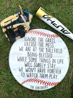 a baseball bat, catchers mitt and sign on the grass with words written in it