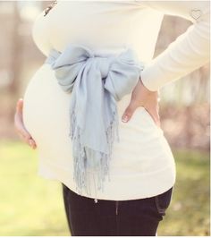 a pregnant woman wearing a white shirt and blue scarf