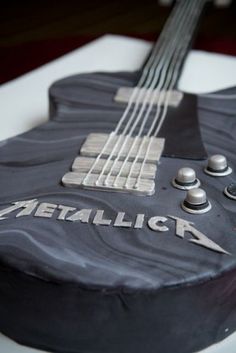 a black guitar cake with metallic lettering on it