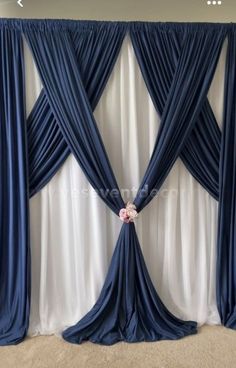 a blue and white drape with flowers on it in front of a wall that has curtains