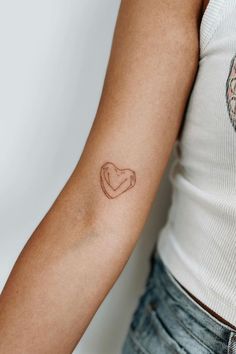 a woman's arm with a small heart tattoo on the left side of her arm