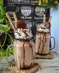 two glasses filled with chocolate milkshakes sitting on top of a table