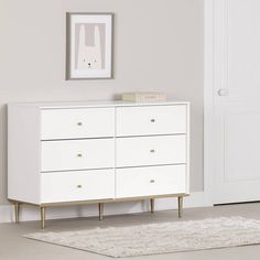 a white and gold dresser in a room with a rug on the floor next to it