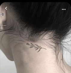 the back of a woman's neck with a small leaf tattoo on her left side