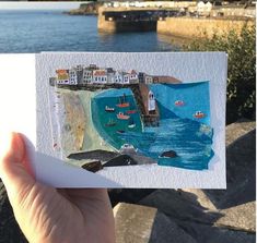 a person holding up a card with boats in the water