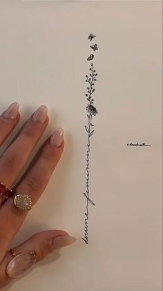 a woman's hand holding a piece of paper with an ink drawing on it