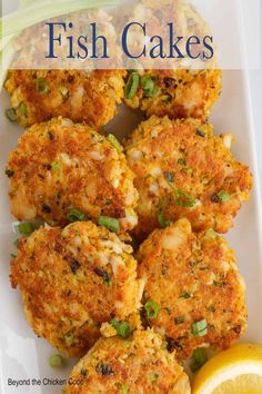 fish cakes on a plate with lemon wedges and garnished with green onions