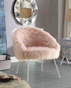 a pink chair sitting on top of a hard wood floor next to a table and mirror