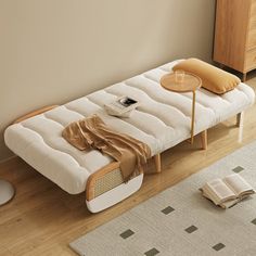 a white futon bed sitting on top of a hard wood floor next to a wooden dresser