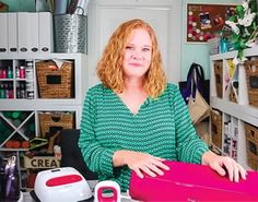 a woman sitting at a desk in front of a sewing machine and other crafting supplies