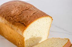 a loaf of white bread sitting on top of a counter next to a slice of bread