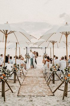 a wedding ceremony on the beach with umbrellas