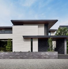 a modern house with black and white brickwork on the outside wall, along with stone steps leading up to it's front door