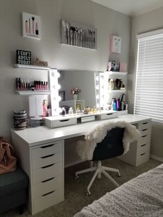 a bedroom with a desk, mirror and lights on it's sides in front of a window