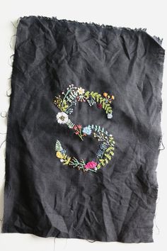 the letter s is made out of black fabric with flowers and leaves on it's side