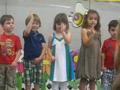 several children are standing in front of a wall and one is holding his hand up