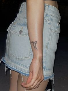 a woman with a tattoo on her arm holding onto a pair of jeans skirt shorts