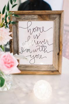 a sign that says home is wherever somewhere youe next to some flowers and a vase