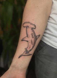 a small shark tattoo on the left arm