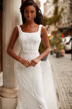 a woman in a white dress leaning against a pillar